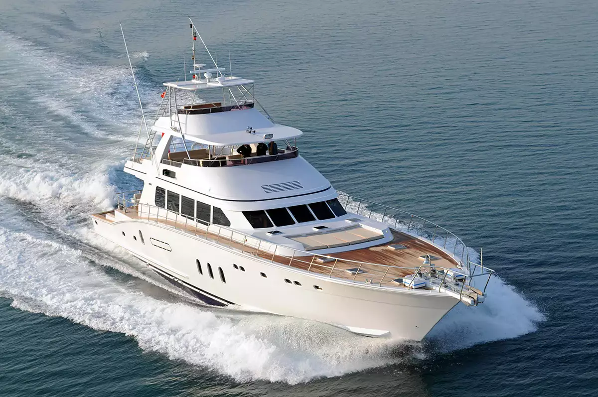 White luxury yacht cruising across open water, creating waves as it moves through the sea.