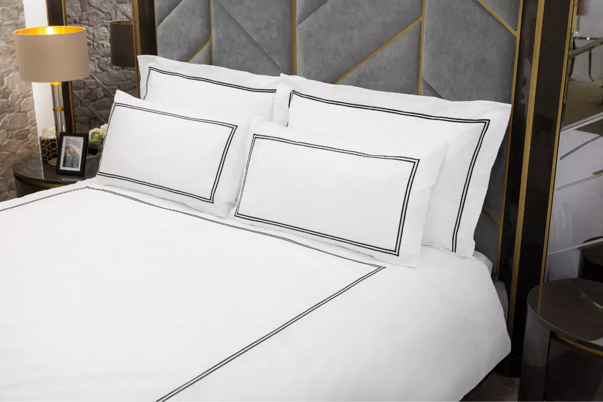 Elegant luxury bedding set featuring crisp white cotton with refined black border embroidery, styled in a contemporary hotel-inspired bedroom for a sophisticated monochrome finish