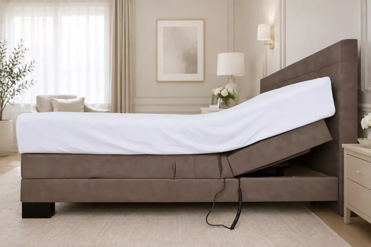 Side view of an adjustable bed with a white mattress and brown upholstered frame, shown raised at the head and foot.